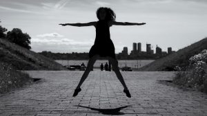 A dynamic black and white silhouette of a woman jumping with arms outstretched in Tallinn, Estonia.