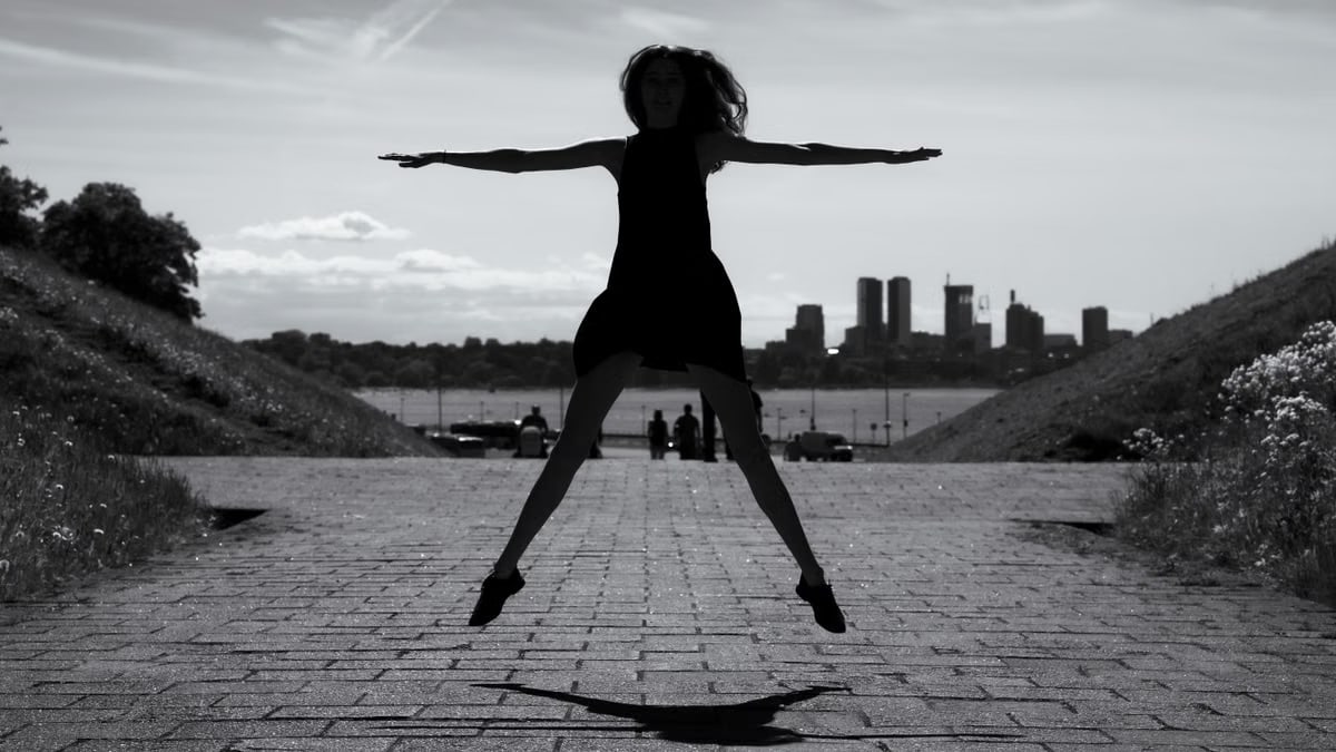 A dynamic black and white silhouette of a woman jumping with arms outstretched in Tallinn, Estonia.